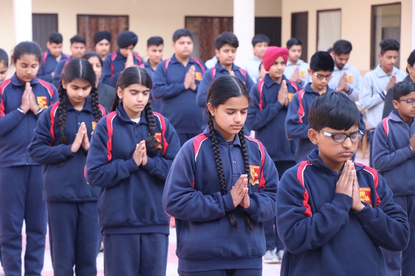 Students standing together with folded hands during the morning assembly prayer