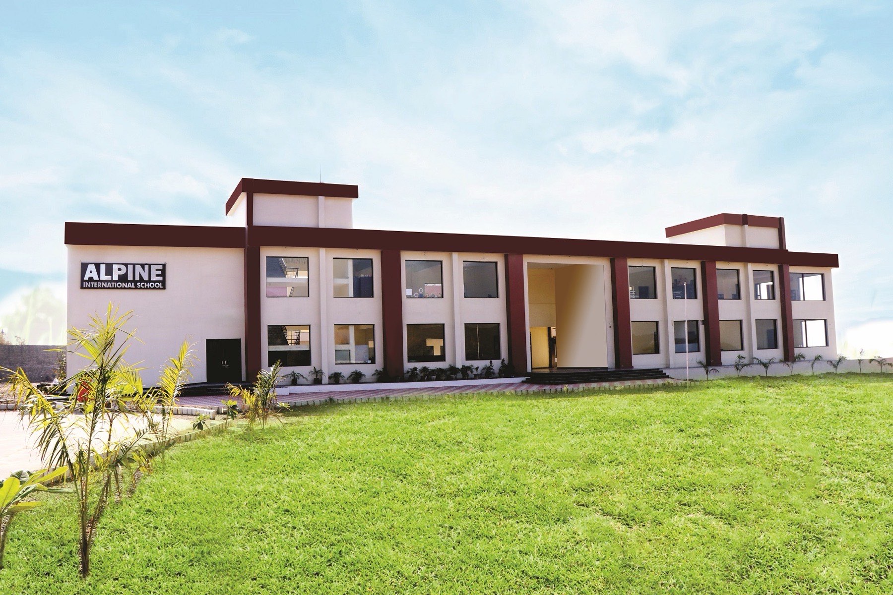 The Alpine International School campus building with green lawns under a clear sky