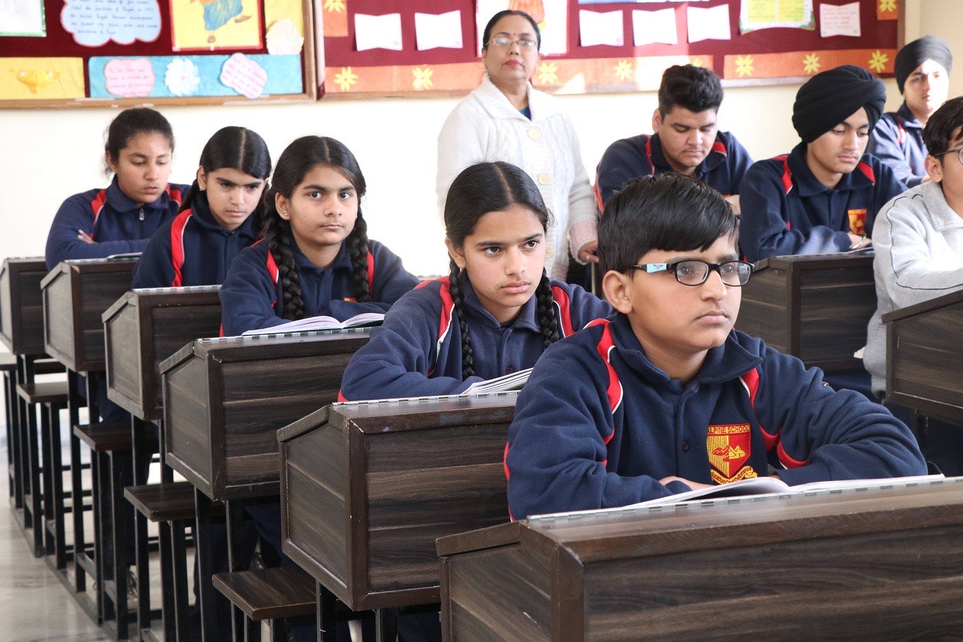 Students seated attentively at wooden desks during a lesson